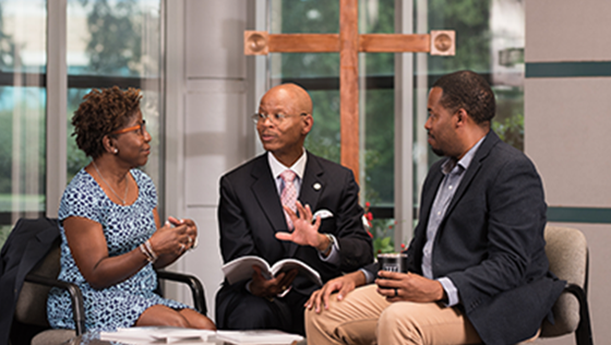 Male reverend speaks to AA couple in church setting