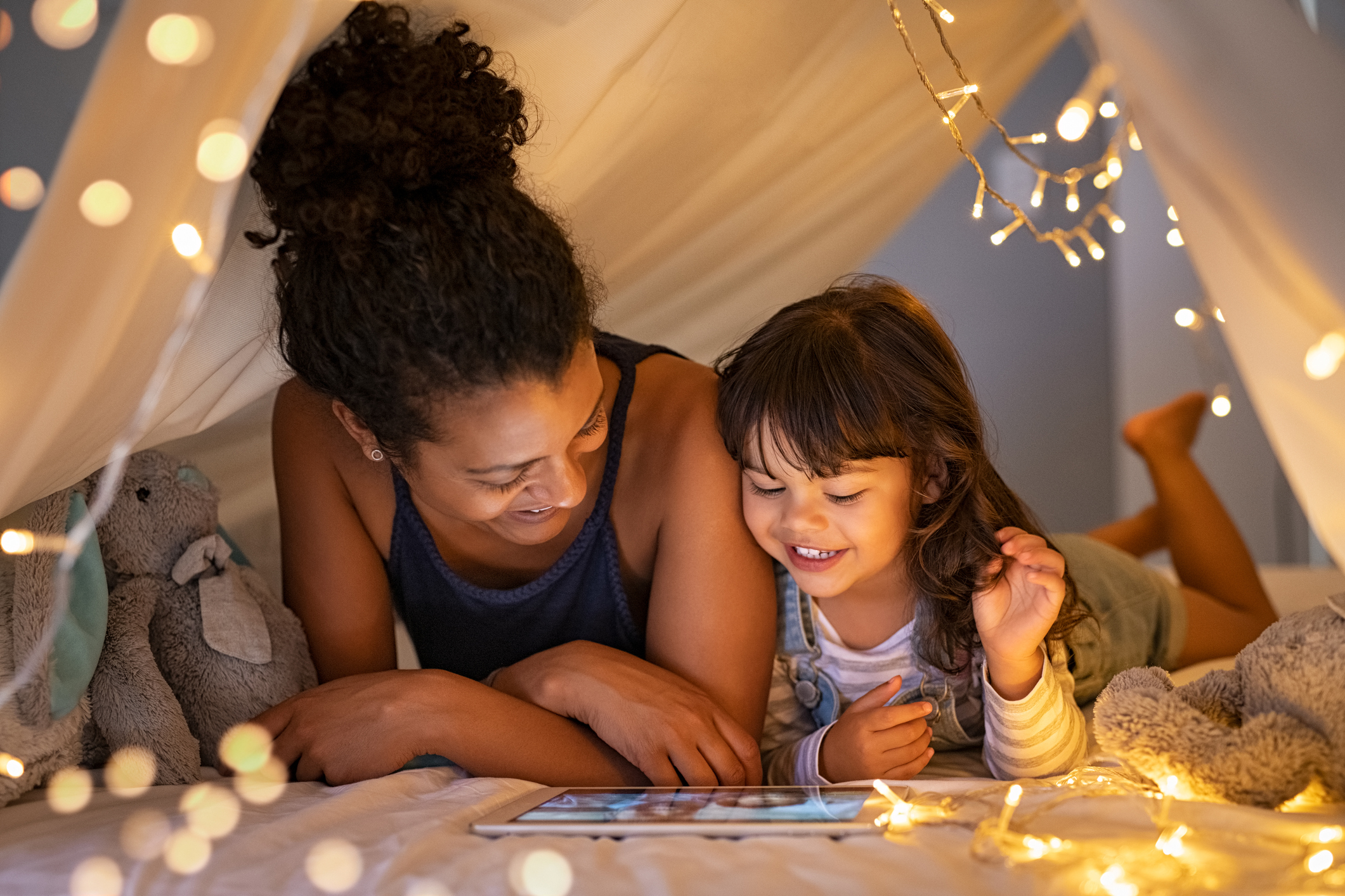 A mother and daughter read a book in a tent