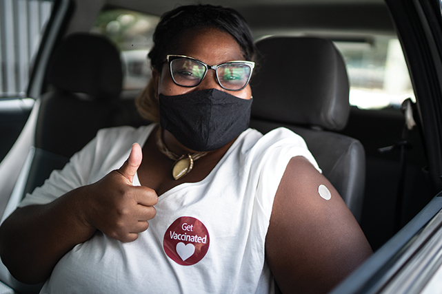 A woman gives a thumbs up after receiving a vaccine